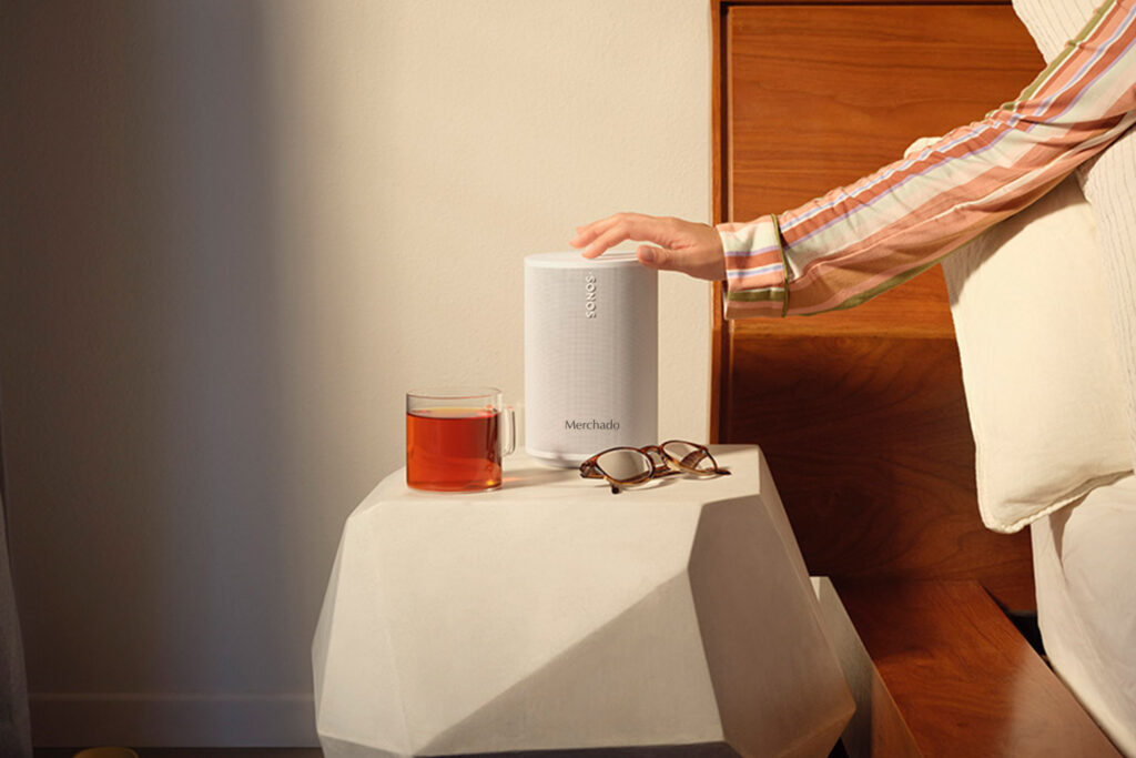 Witte Sonos Move 2 speaker met logo, geplaatst op een nachtkastje naast een kop thee