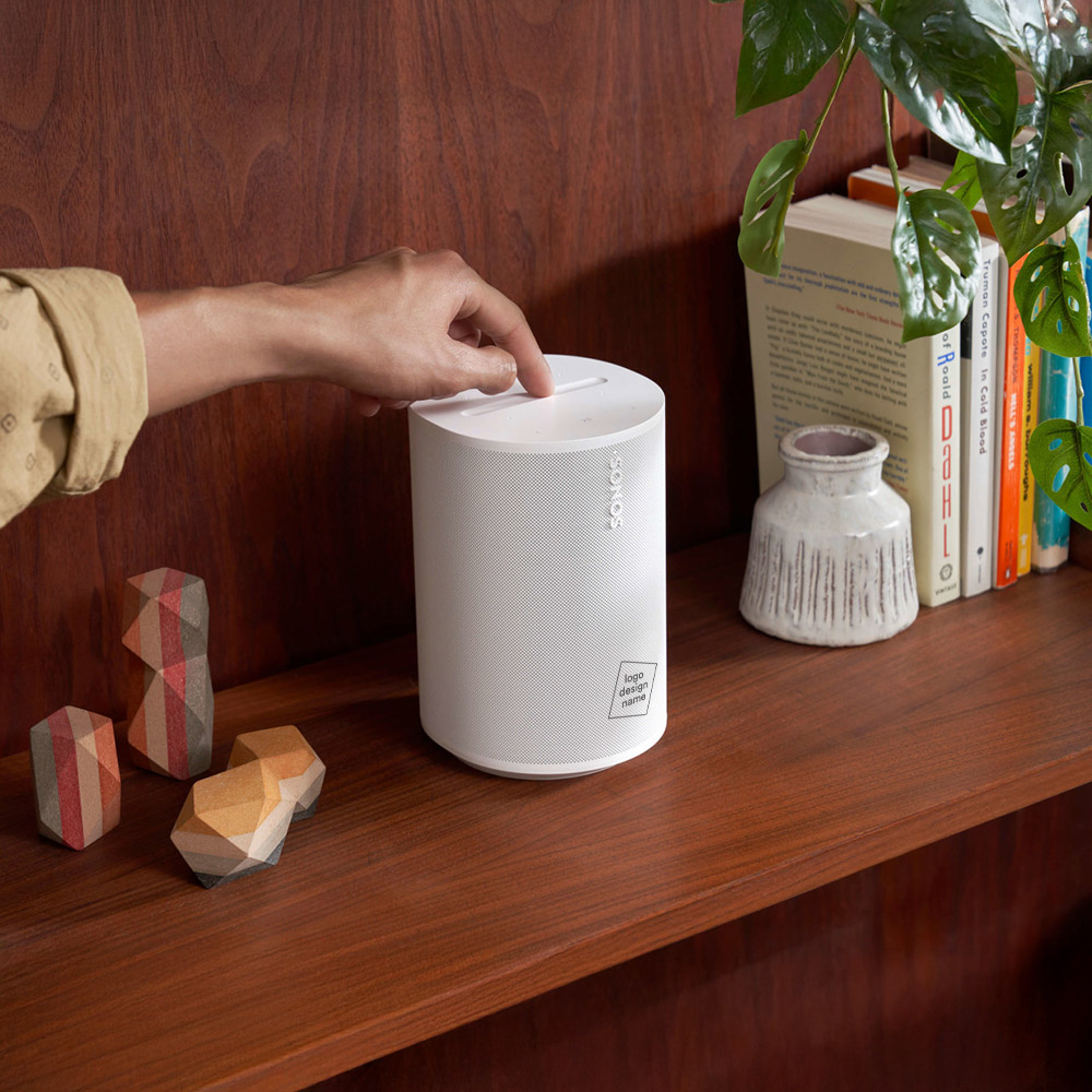 Witte Sonos Era 100 speaker met gepersonaliseerd logo op een houten plank, gebruikt als stijlvol relatiegeschenk